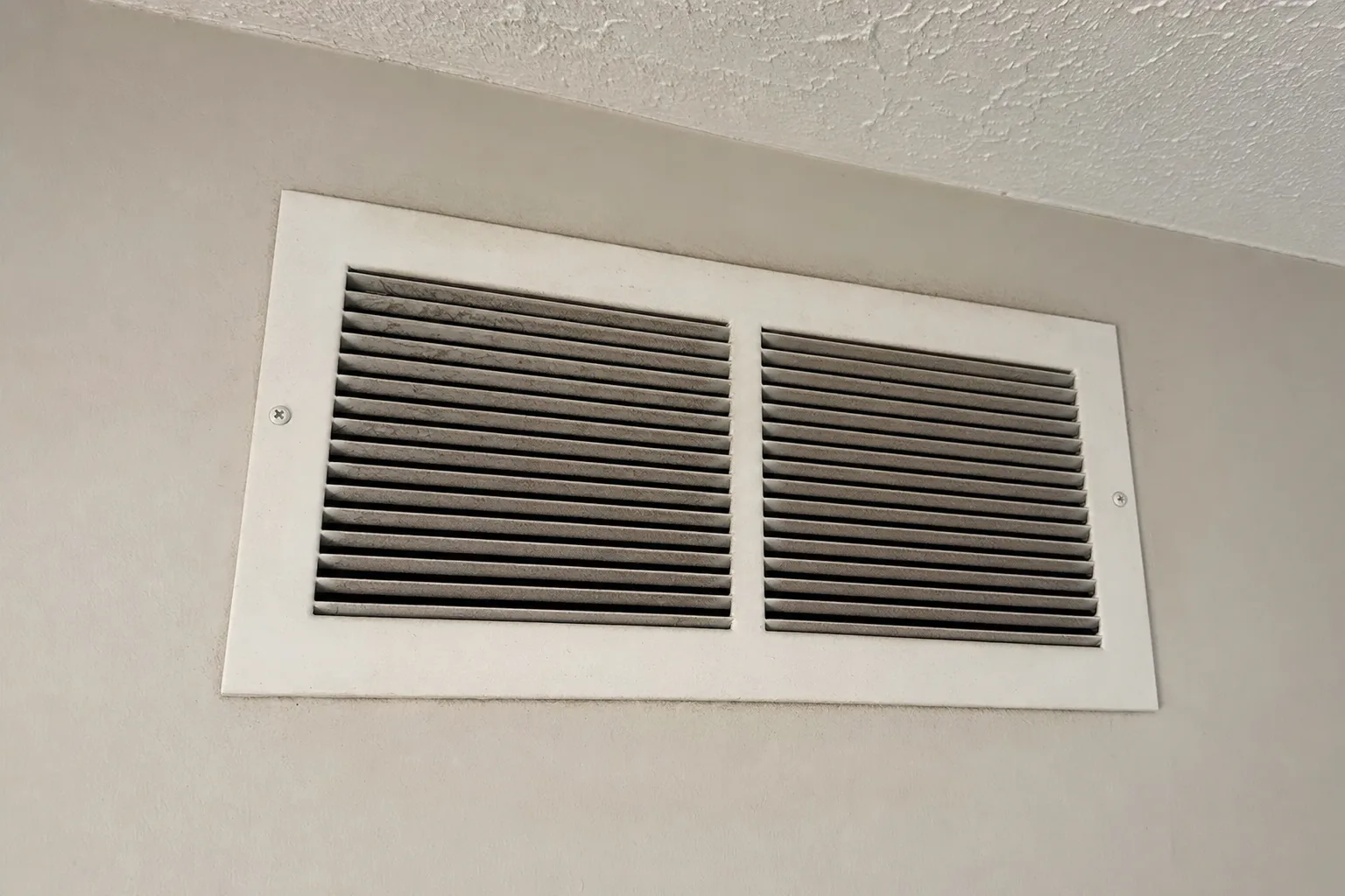 Wall register with dark dust streaking around the louvers, a common way airborne particulates move through a home's air.