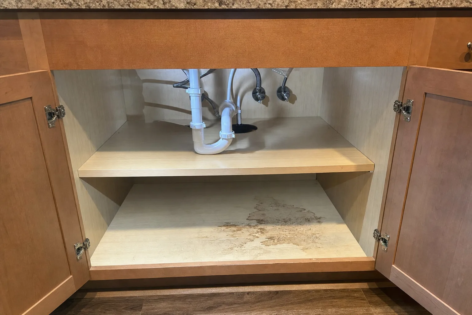 Open kitchen sink cabinet with plumbing lines reviewed during a York Pennsylvania mold inspection.